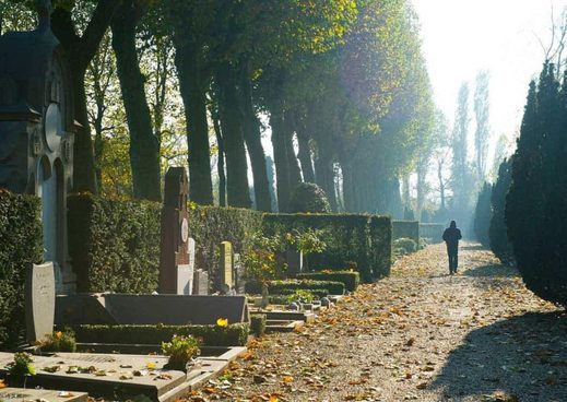 Osoba idąca przez cmentarz w poszukiwaniu grobu bliskiej osoby