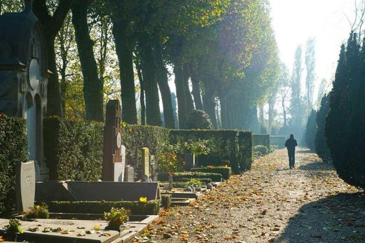 Osoba idąca przez cmentarz w poszukiwaniu grobu bliskiej osoby